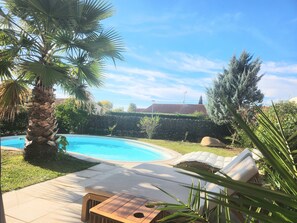 A swimming pool with lounge chairs, a palm tree, and a hedge. - Cosy House With Swimming Pool - Bergerac (5 minutes from downtown) (Bergerac)