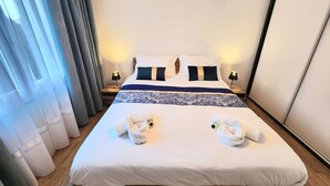 A hotel room with a bed, two bedside lamps, a nightstand, and a large window with curtains. - Cosy House With Swimming Pool - Bergerac (5 minutes from downtown) (Bergerac)