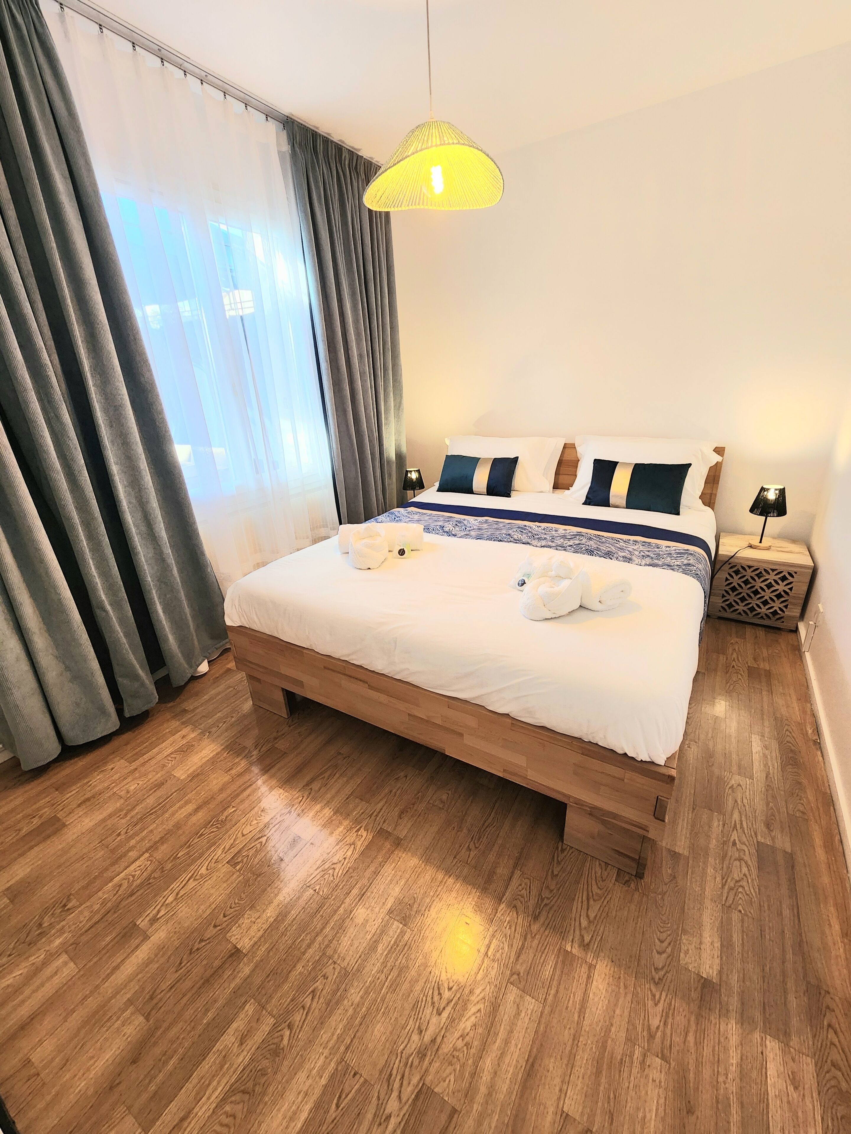 A neatly made bed with a white duvet, a wooden headboard, and a bedside lamp.