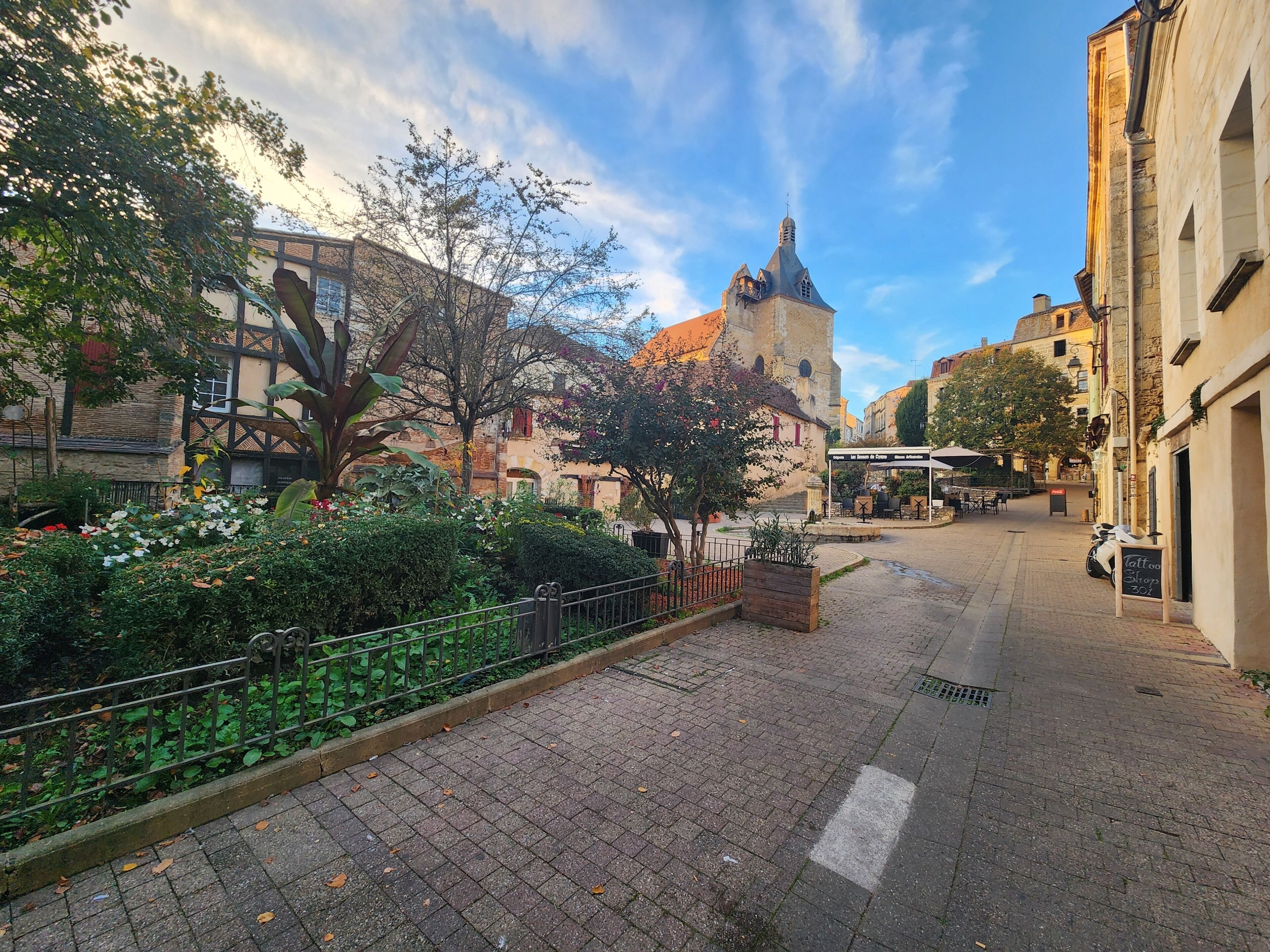 Eine Kopfsteinpflasterstraße mit einer Kirche, einem Café und einem Schild für ein Tattoo-Studio.