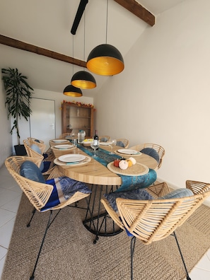 A dining area with a round table, wicker chairs, and hanging pendant lights. - Cosy House With Swimming Pool - Bergerac (5 minutes from downtown) (Bergerac)