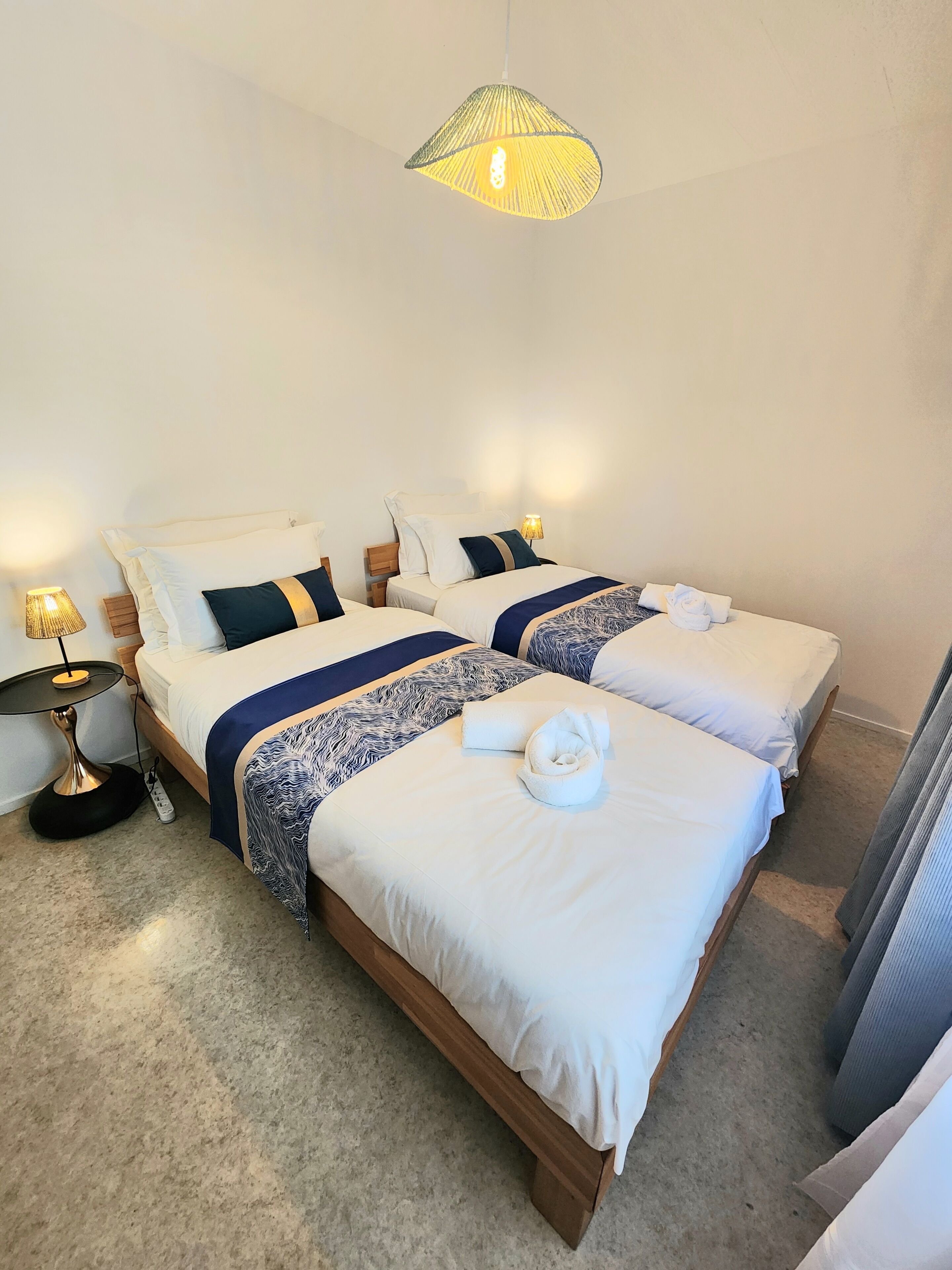 Une chambre double avec deux lits, une petite table et une lampe.