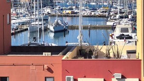 A marina with multiple sailboats docked, a red building in the foreground, and a clear blue sky. - Apartment in cosy residence with magnificent view of the port (Occitanie)