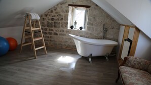 A room with a stone wall, a wooden ladder, a white bathtub, and a wooden floor. - Golubica: A Romantic 17th Century Stone UNESCO Retreat (Stari Grad)