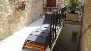 A sun lounger with a stone wall and a window with a brown shutter. - Golubica: A Romantic 17th Century Stone UNESCO Retreat (Stari Grad)