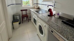 A compact kitchen with a washing machine, a microwave, and a sink.