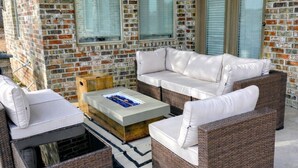 Eine überdachte Terrasse mit Korbmöbeln, einem Flachbildfernseher und einem Deckenventilator.
