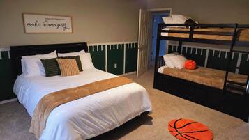 A bedroom with a bed, a bunk bed, a ceiling fan, a motivational quote on the wall, and two sports-themed rugs.