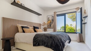 Un dormitorio moderno con una cama grande, una mesita de noche, una ventana con vistas y una lámpara de techo.