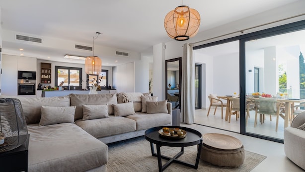Una sala de estar moderna con un sofá modular, una mesa de centro redonda y un comedor con muebles de madera.