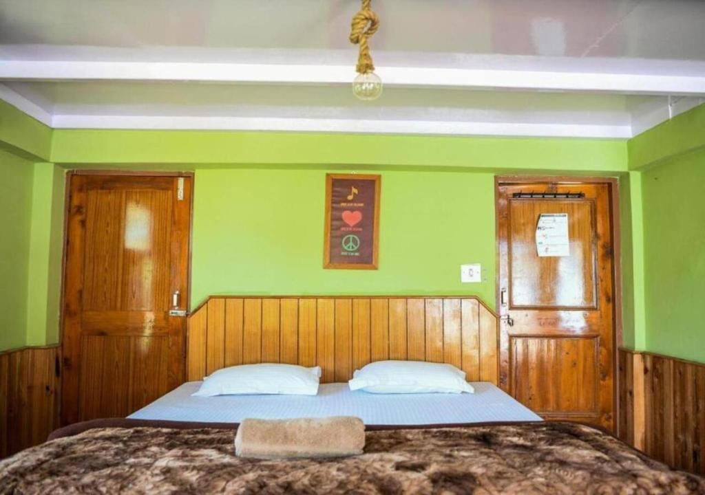 Ein Einzelbett mit hölzernem Kopfteil, zwei Kissen und einer Decke.