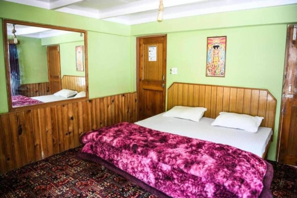 A room with a wooden headboard bed, a large mirror, and a patterned rug.
