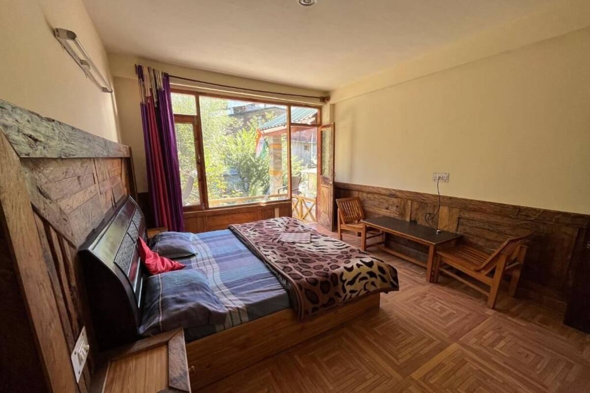 A room with a bed, a bench, and a window with curtains.