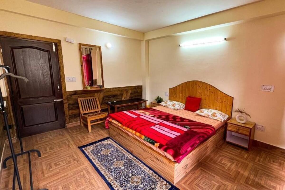 A bedroom with a wooden bed, a nightstand, a bench, a mirror, and a door.
