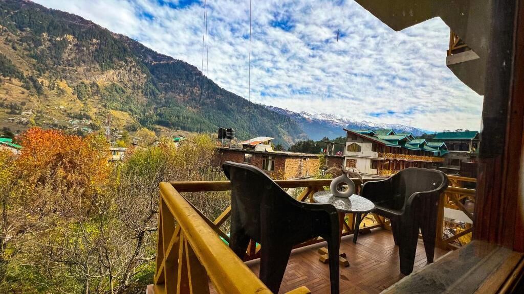 Una terraza con mesa y sillas con vistas a un paisaje montañoso.