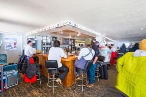 Una zona de bar con taburetes, una barra y un panel con la carta.