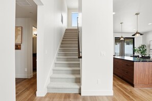 Una cocina moderna con una isla de madera, una escalera y vistas al cielo.