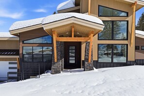 Un edificio moderno de varios pisos con tejado nevado y grandes ventanales.