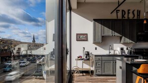 Une cuisine moderne donnant sur une rue de la ville, avec une roue de vélo et un panneau indiquant « FRAIS ».