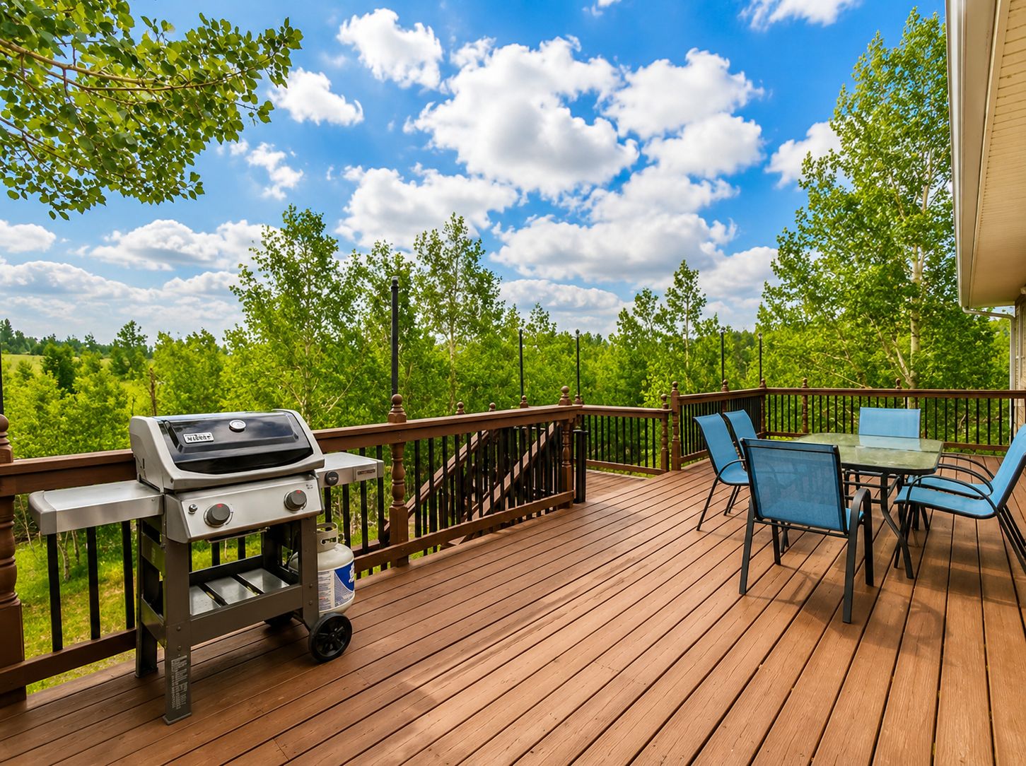 Eine Holterrasse mit Grill, Stühlen und einem Tisch.