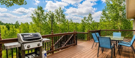 Eine Holterrasse mit Grill, Stühlen und einem Tisch.