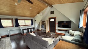 Ein Loft-Wohnzimmer mit Essbereich, einer Couch, einem Fernseher und einem Deckenventilator.