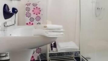 Ein Badezimmer mit einem weißen Waschbecken, einem Handtuchhalter und einer Duschkabine.