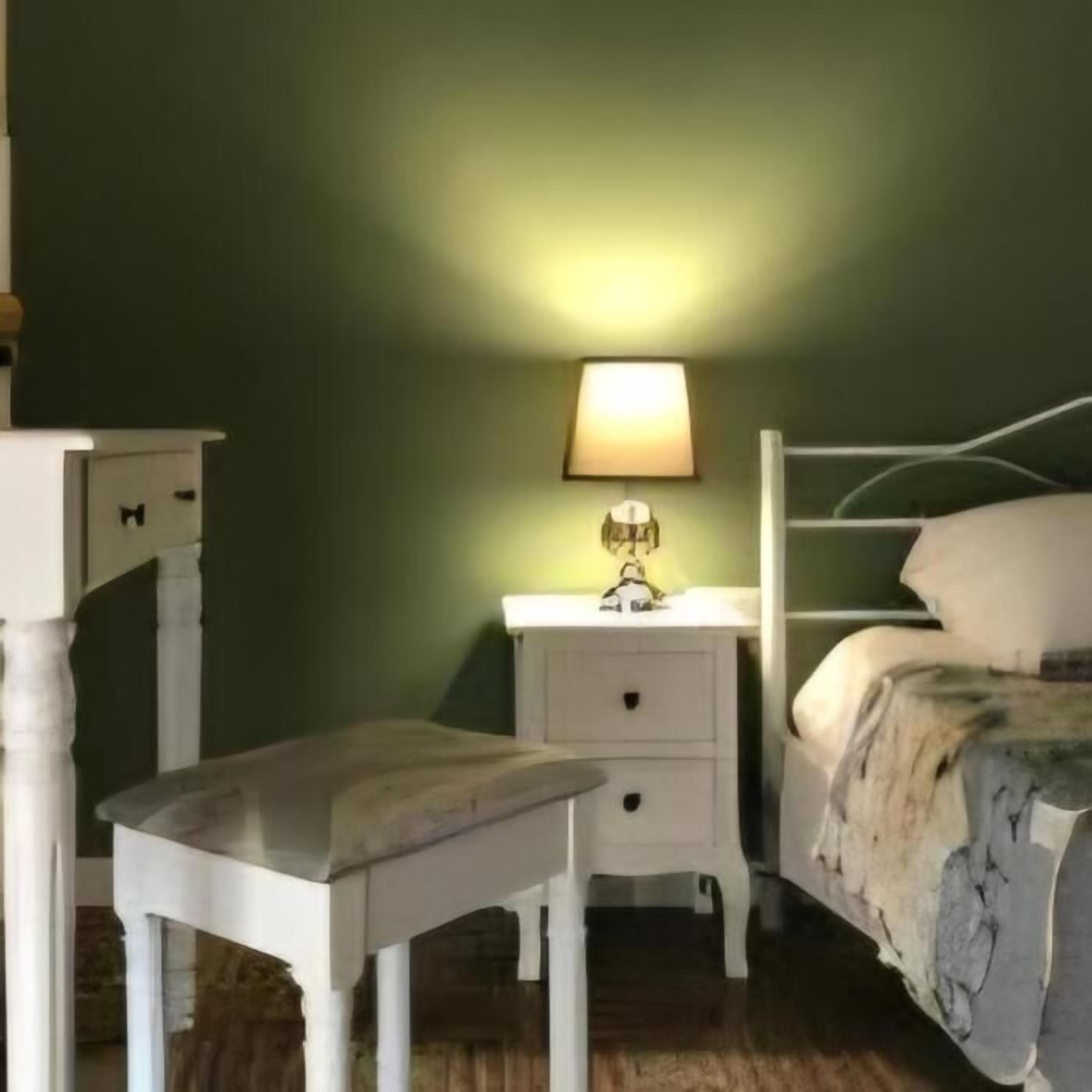 A bedroom with a bed, a nightstand, a lamp, and a small table.