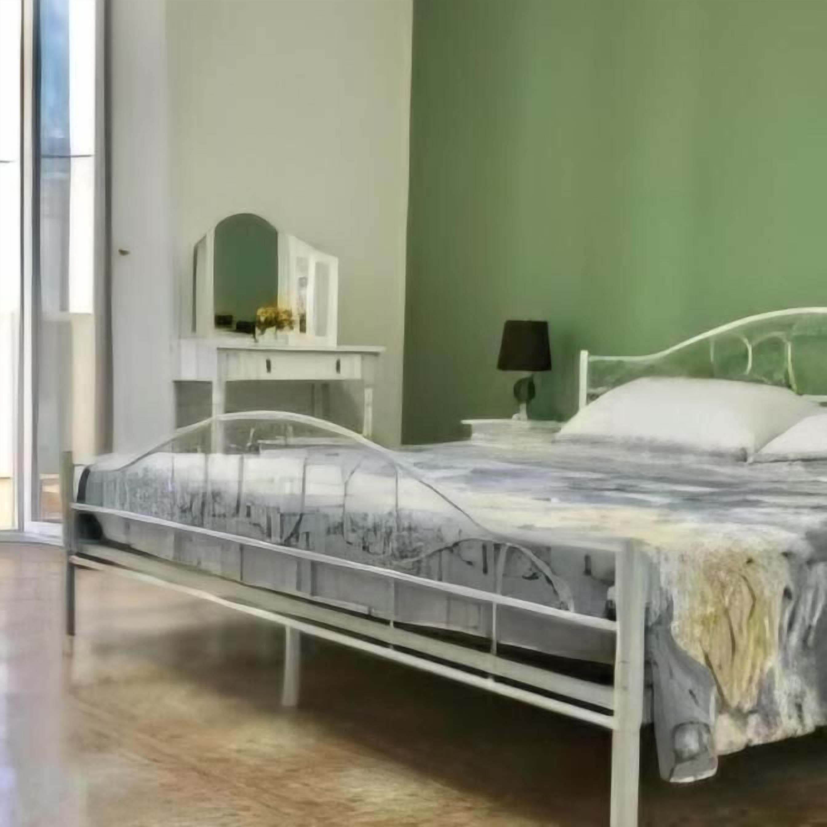 A bedroom with a bed, a bedside table with a lamp, a dresser, and a mirror.