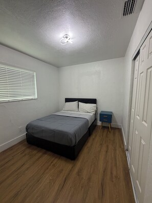A bedroom with a bed, a nightstand, a wardrobe, and a window with blinds. - Terrific 2-bedroom townhome with AC in vibrant Miami (Miami)