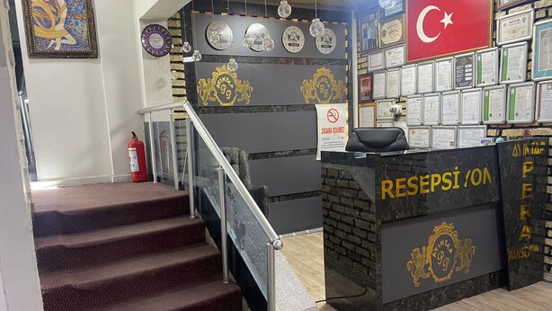 Un mostrador de recepción con un letrero, una escalera y una pared con relojes y diplomas.