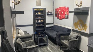 Un área de estar moderna con un sofá, dos sillones, una mesita de centro y una estantería decorativa con premios.