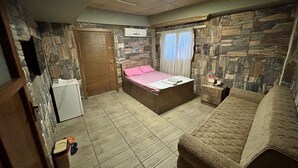 Un dormitorio con cama, cómoda, armario y pared de piedra.