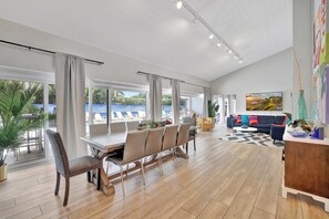 A spacious living area with a dining table, chairs, a sofa, and a large painting. - Beachfront Bliss: 6 Bedroom Home with Heated Pool (Fort Lauderdale)