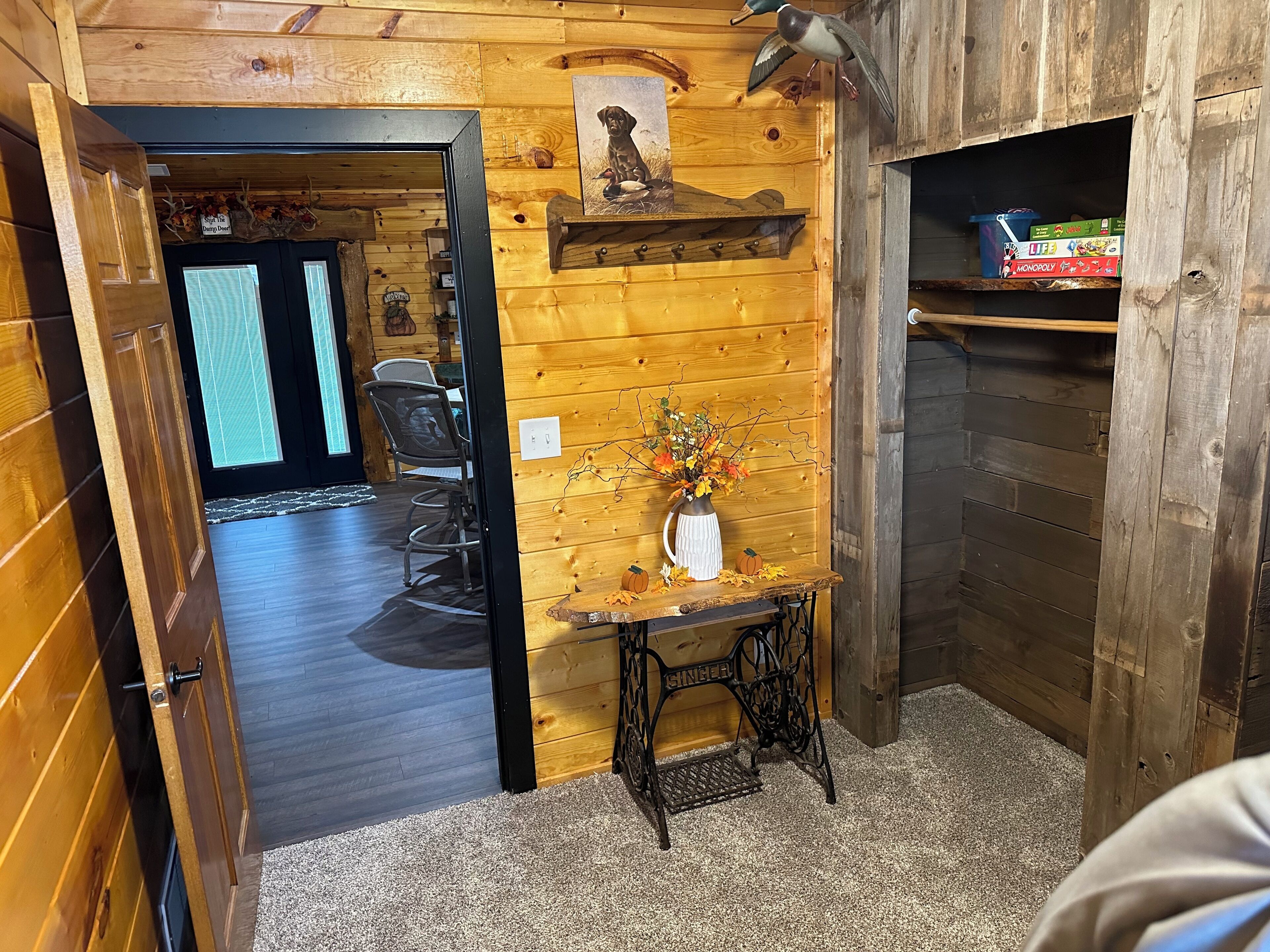 Ein Holzinterieur mit Essbereich, einem kleinen Tisch mit einer Vase und einem Regal mit Gesellschaftsspielen.