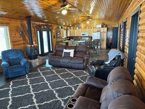 A cozy log cabin interior with a fireplace, leather sofas, a dining area, and a kitchen. - Cozy lake cabin along the Platte River. (Columbus)