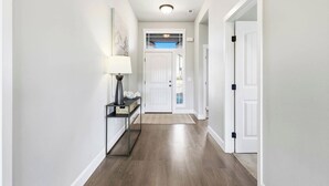 A hallway with a wooden floor, white walls, and a door at the end. - Haven in the Desert - Kennewick spacious home (Kennewick)