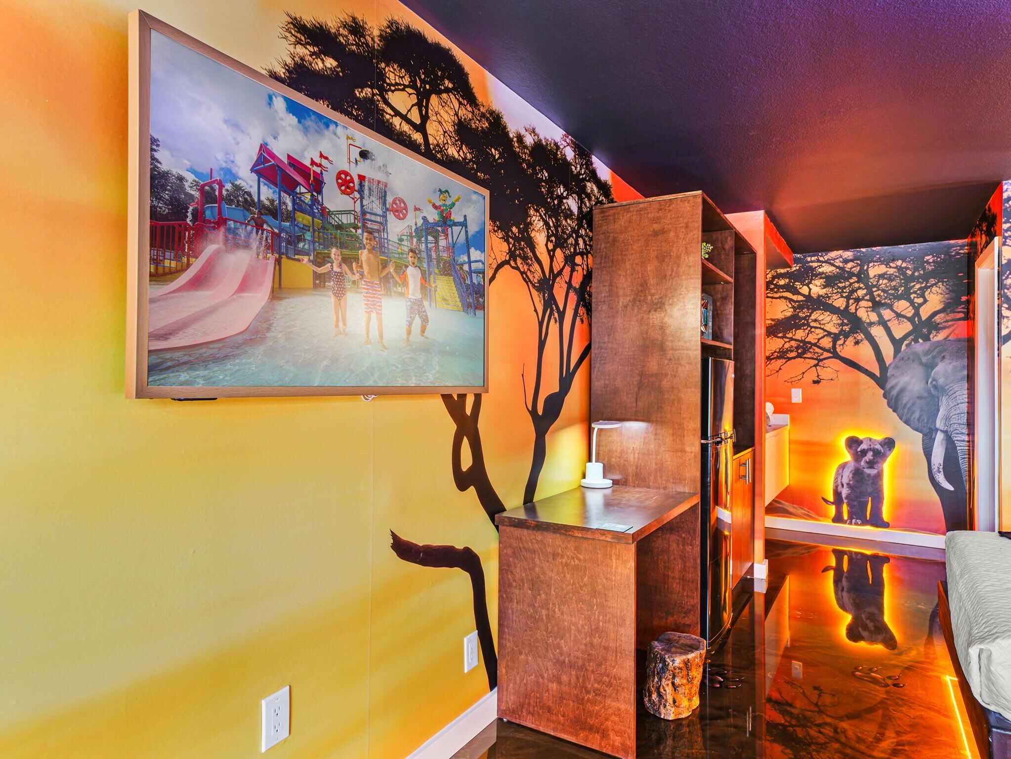 A room with a mural of a playground, a wooden desk, and a shelf with a stuffed animal.
