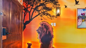 A room with a wooden door, a lion mural, a tree, and a wall-mounted light fixture. - Lion King studio w/ pool & workspace (Kissimmee)