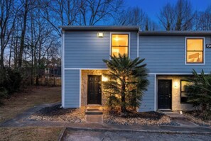 A two-story house with a stone entrance, a small porch, and a well-lit front door. - Premium Townhome #A w/ 2 King Beds & Luxury Baths (Peachtree Corners)