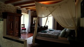 Ein Schlafzimmer mit Baldachinbett, Holzmöbeln und Steinwänden.