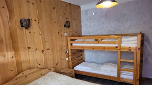 Una cama litera con cabecera de madera, una mesita de noche y una lámpara fijada a la pared.