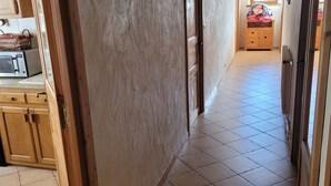 Un pasillo con armarios de madera, un microondas y suelo de baldosas.