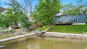 A residential area with a bridge over a pond, houses, and a lawn. - Lakefront Oasis w/ Private Dock + Paddle Boards (Lake Ozark)