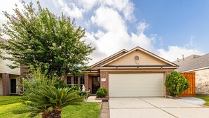 A single-story house with a garage, a well-maintained lawn, and a large tree in the front yard. - Casa de Capucine: Timeless Elegance & Grand Interiors. (Humble)