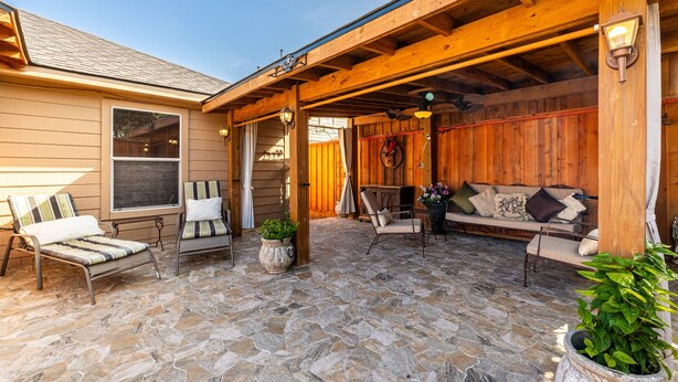 A covered patio with stone flooring, wooden furniture, and a wooden wall. - Casa de Capucine: Timeless Elegance & Grand Interiors. (Humble)