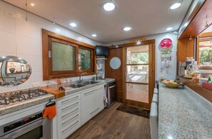 Une cuisine moderne dotée de plans de travail en granit, d’une cuisinière à gaz, de meubles blancs et d’une grande fenêtre.