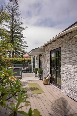 A modern house with a stone facade, a wooden deck, and a hanging chair. - Large Yard, Walk to Beach and Restaurants (San Diego)