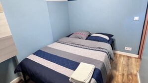 A bedroom with two beds, a wooden floor, and a blue accent wall. - Quiet apartment in the heart of the Cours Julien (Marseille)