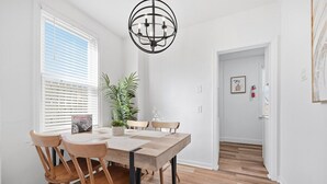 Ein Essbereich mit Holztisch und Stühlen, einer Chandelier und einem Blumentopf.
